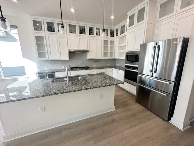 a kitchen with stainless steel appliances granite countertop a refrigerator a stove and a sink