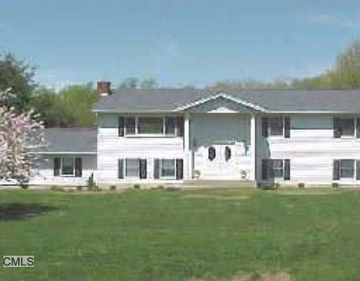 a front view of a house with a garden and trees