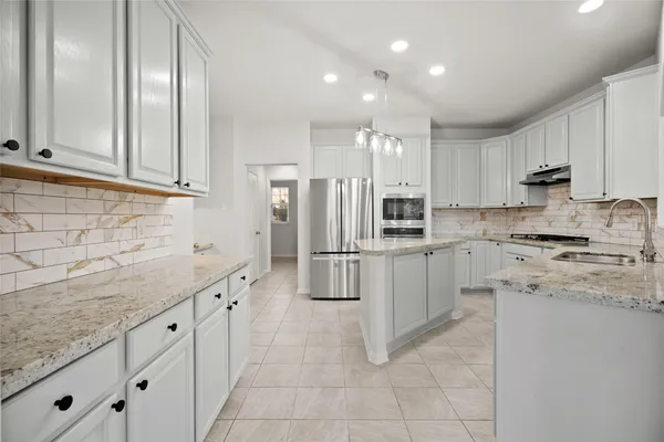 a kitchen with granite countertop a sink stove and refrigerator