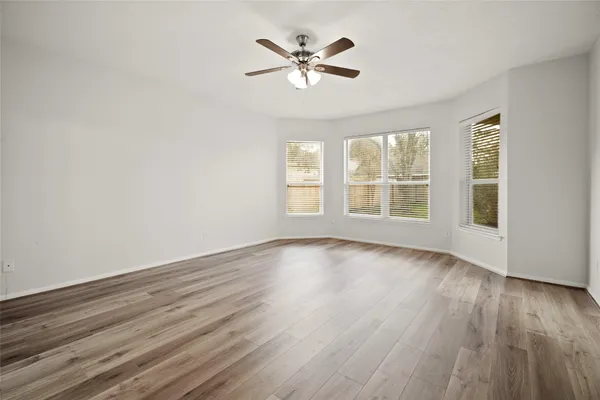 an empty room with wooden floor and ceiling fan