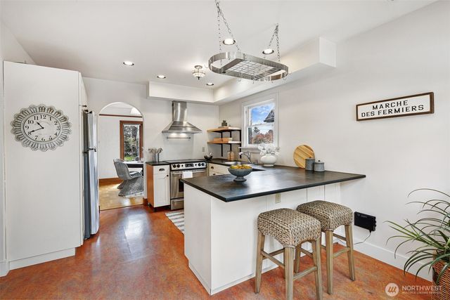 a kitchen with stainless steel appliances granite countertop a sink a stove a refrigerator and chairs