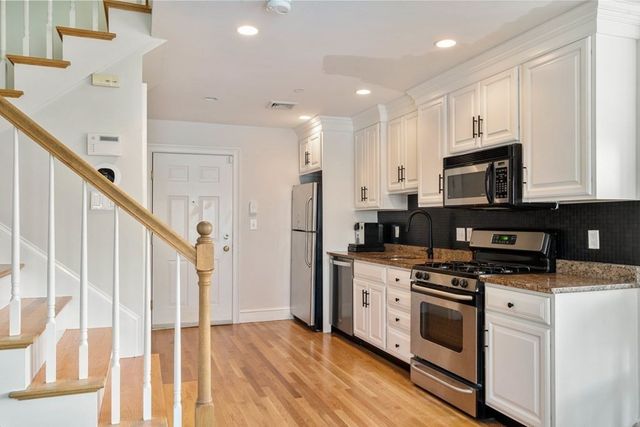 a kitchen with stainless steel appliances granite countertop a stove a sink and a refrigerator