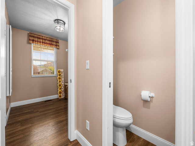 6849 North Black Powder Road Mountain Green, UT 84050 - Photo 26 of 43 Interior hallway featuring wood-finish flooring, a window with horizontal blinds, and a flush-mount ceiling light