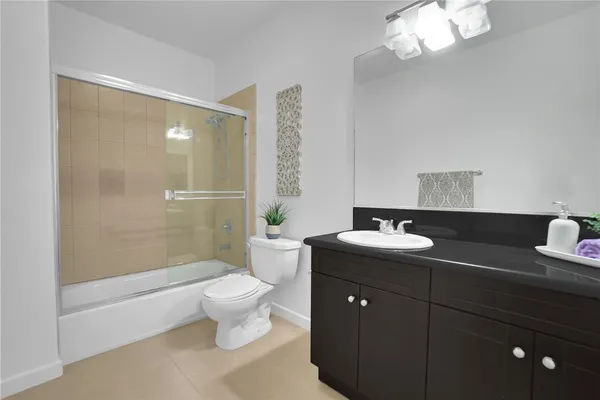 a bathroom with a granite countertop sink a toilet a mirror and shower