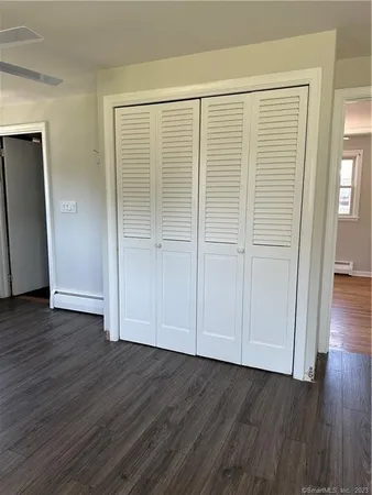 an empty room with wooden floor and closet area