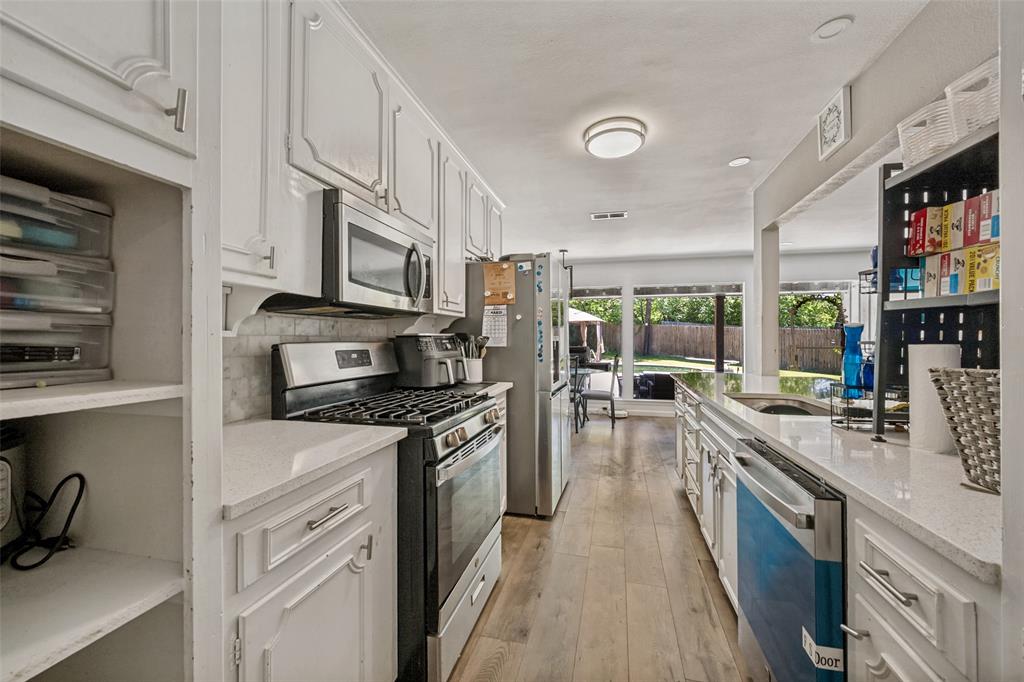 625 Caduceus Lane Hurst, TX 76053 - Photo 9 of 21 a kitchen with stainless steel appliances granite countertop a stove top oven a sink a refrigerator white cabinets and wooden floor