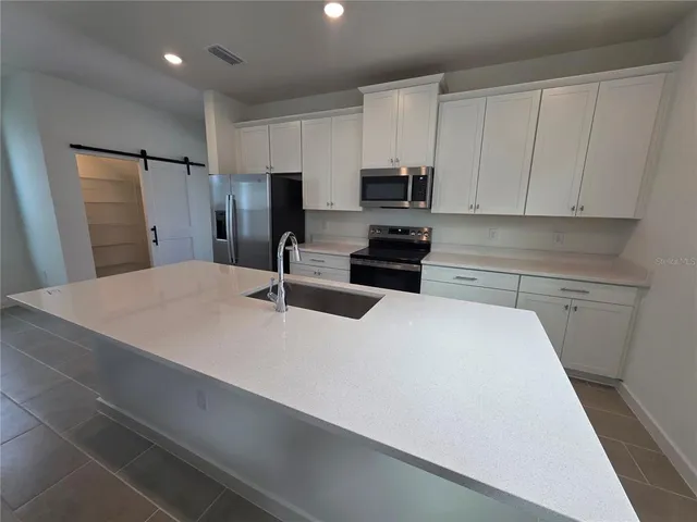 a kitchen with stainless steel appliances a refrigerator sink and microwave