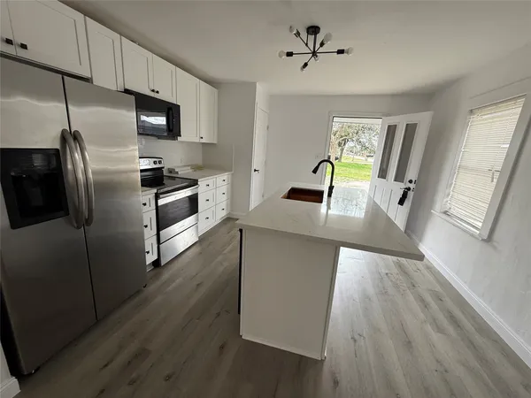 a kitchen with cabinets a counter space stainless steel appliances and a window