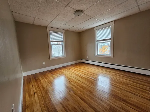 an empty room with wooden floor and windows