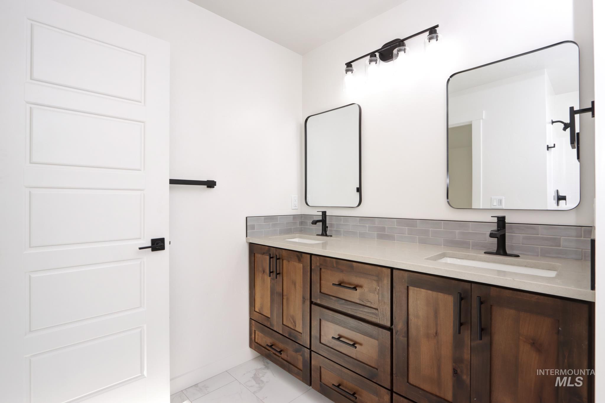 848 North 5th Street Nyssa, OR 97913 - Photo 24 of 49 Dual vanity featuring wood-finish cabinetry, light-toned countertops, and matte black fixtures