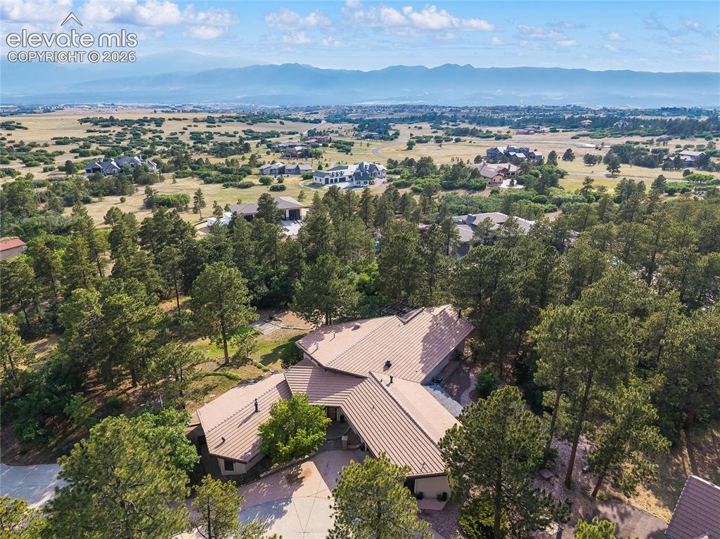 12730 Bridle Bit Road Colorado Springs, CO 80908 - Photo 47 of 50 Sprawling residential property featuring a multi-level structure with a brown tile roof, surrounded by mature evergreen trees