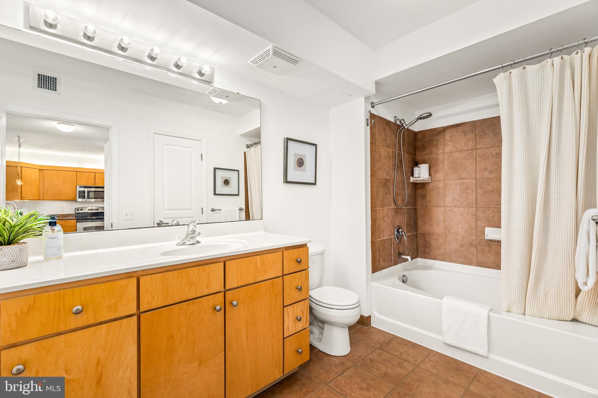 616 E Street Northwest, Unit 322 Washington, DC 20004 - Photo 19 of 33 a bathroom with a granite countertop sink mirror bathtub and toilet