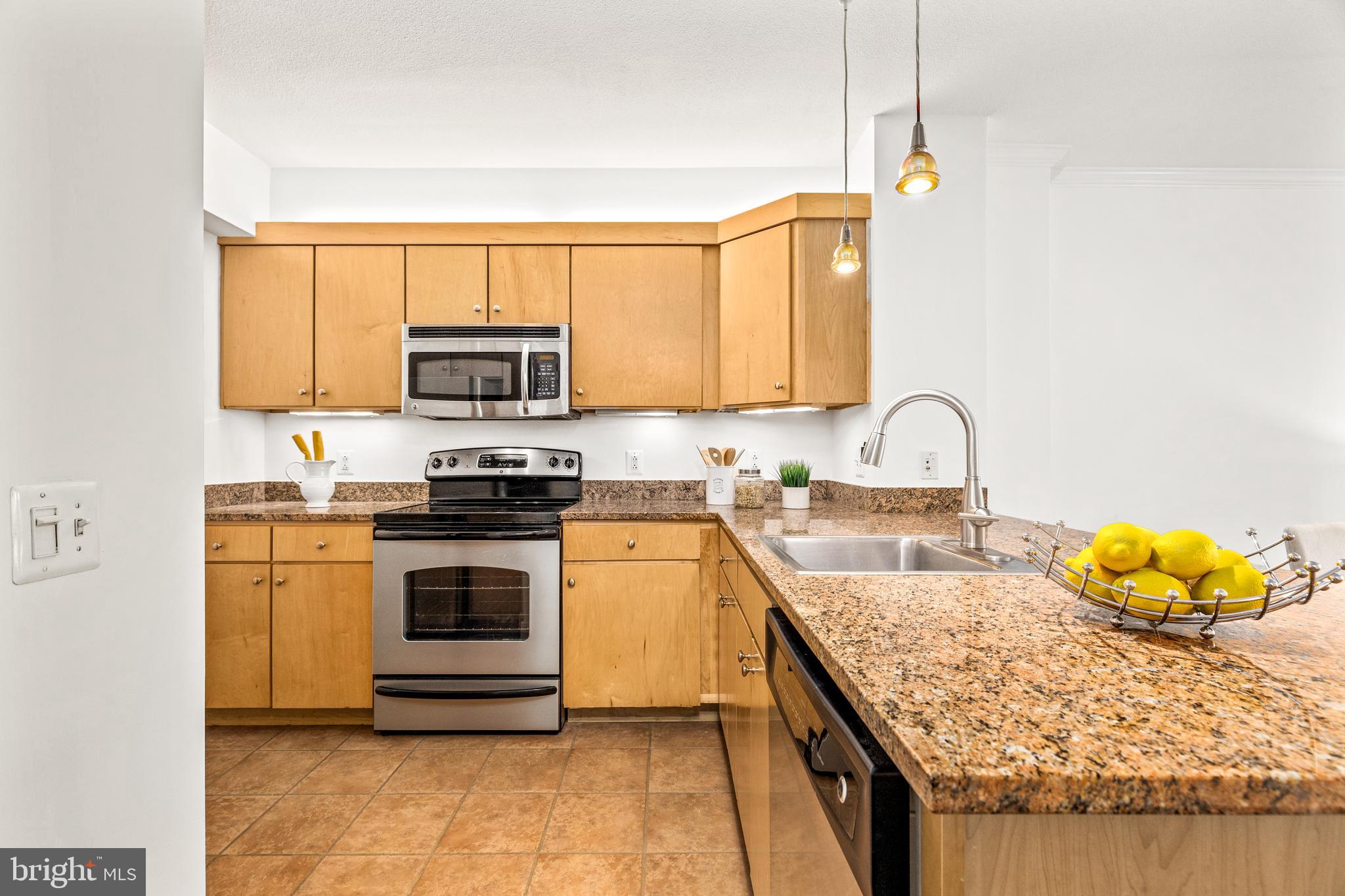 616 E Street Northwest, Unit 322 Washington, DC 20004 - Photo 8 of 33 a kitchen with stainless steel appliances granite countertop a stove a sink and a microwave