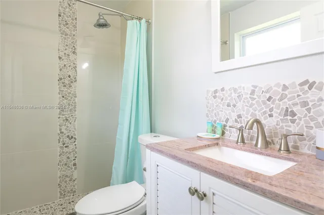 a bathroom with a granite countertop sink toilet and shower