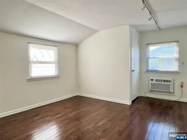 an empty room with wooden floor cabinet and windows