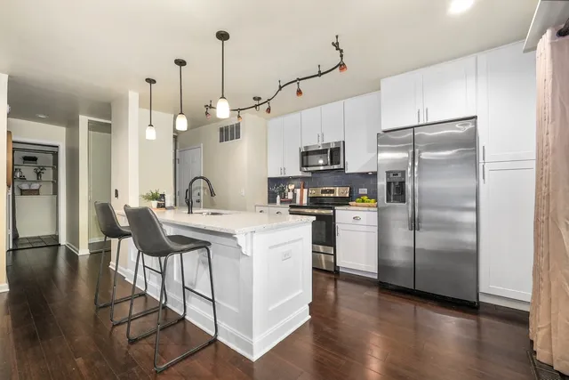 a kitchen with kitchen island white cabinets and stainless steel appliances