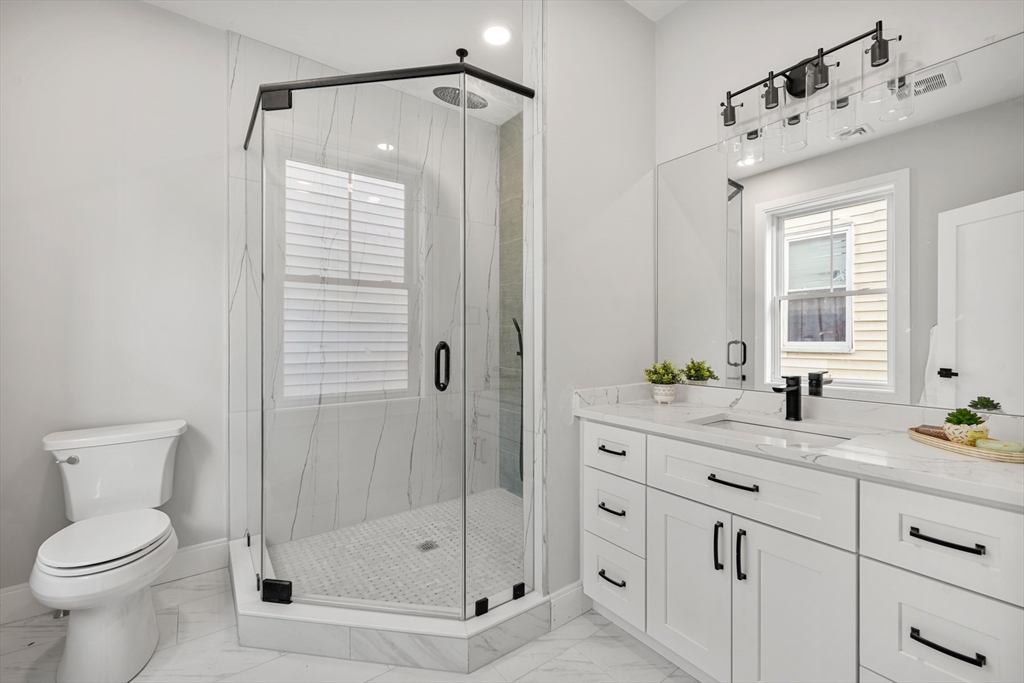 60 Fuller Street, Unit PH5 Boston, MA 02124 - Photo 16 of 32 a bathroom with a shower sink vanity mirror and toilet
