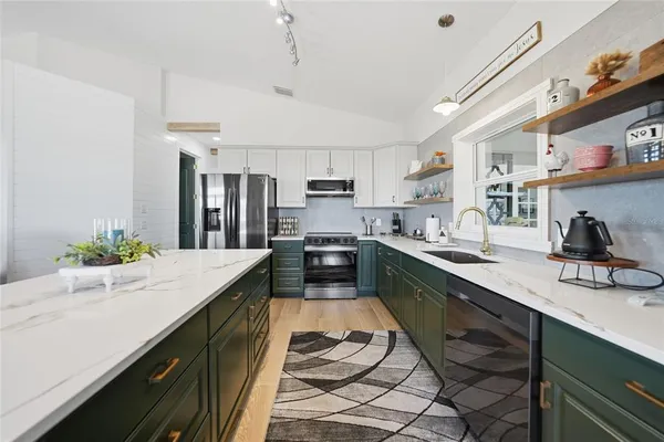 a large white kitchen with a refrigerator a stove a sink a dining table and chairs with wooden floor