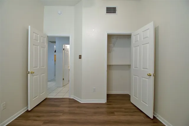 an empty room with wooden floor & closet area