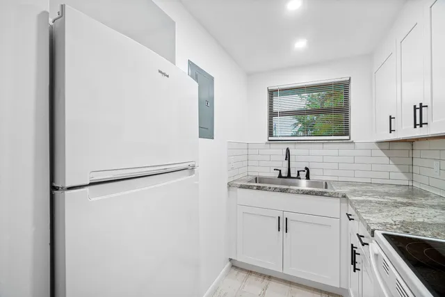 a kitchen with granite countertop white cabinets and white appliances