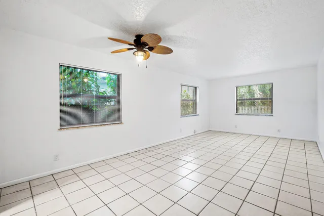 an empty room with windows and fan