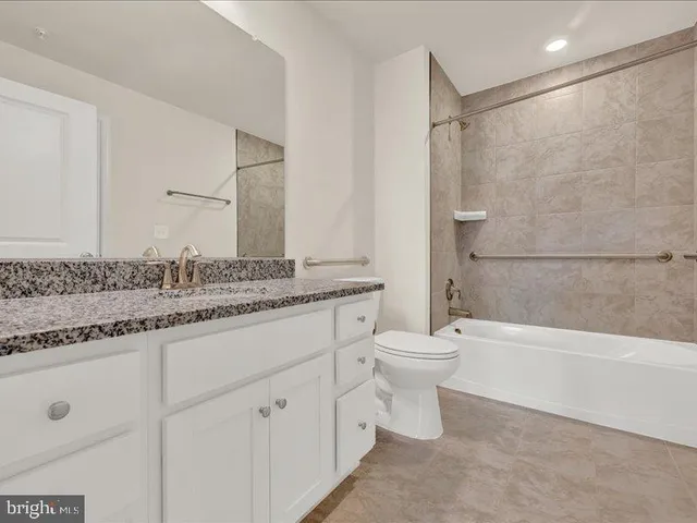 a bathroom with a granite countertop sink a toilet and a bathtub