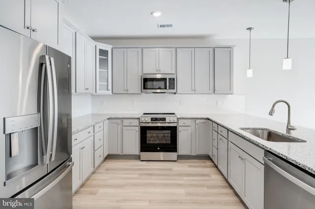 a kitchen with stainless steel appliances granite countertop a stove top oven a sink and a refrigerator