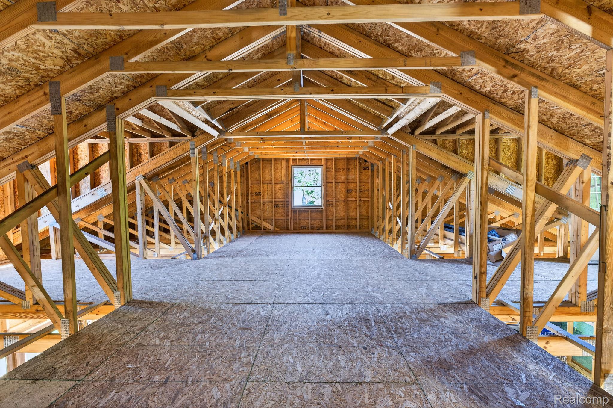 9353 Hill Road Swartz Creek, MI 48473 - Photo 71 of 98 Expansive interior framing showcasing a window, wood trusses, Oriented Strand Board (OSB) subflooring, and exposed wood beams