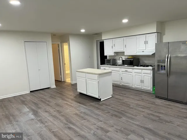 a kitchen with a sink a refrigerator and white cabinets