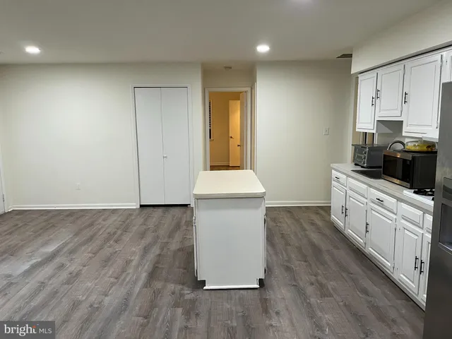 a kitchen with granite countertop white cabinets and wooden floor