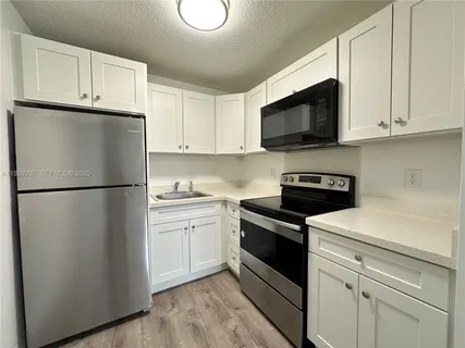 a kitchen with white cabinets and stainless steel appliances