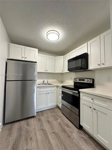 a kitchen with a refrigerator stove and white cabinets