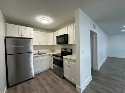 a kitchen with a refrigerator a stove top oven and wooden floor