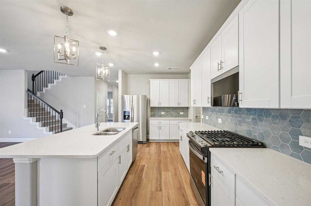 505 Stagg Street McKinney, TX 75069 - Photo 13 of 39 a large white kitchen with a stove top oven a sink a counter space and cabinets