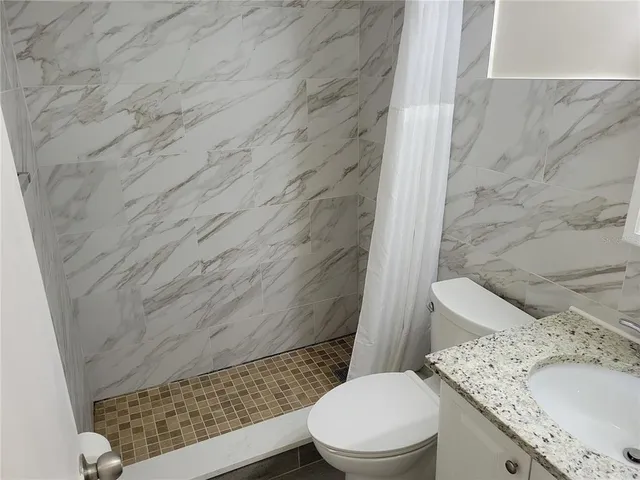 a bathroom with a granite countertop toilet and a sink