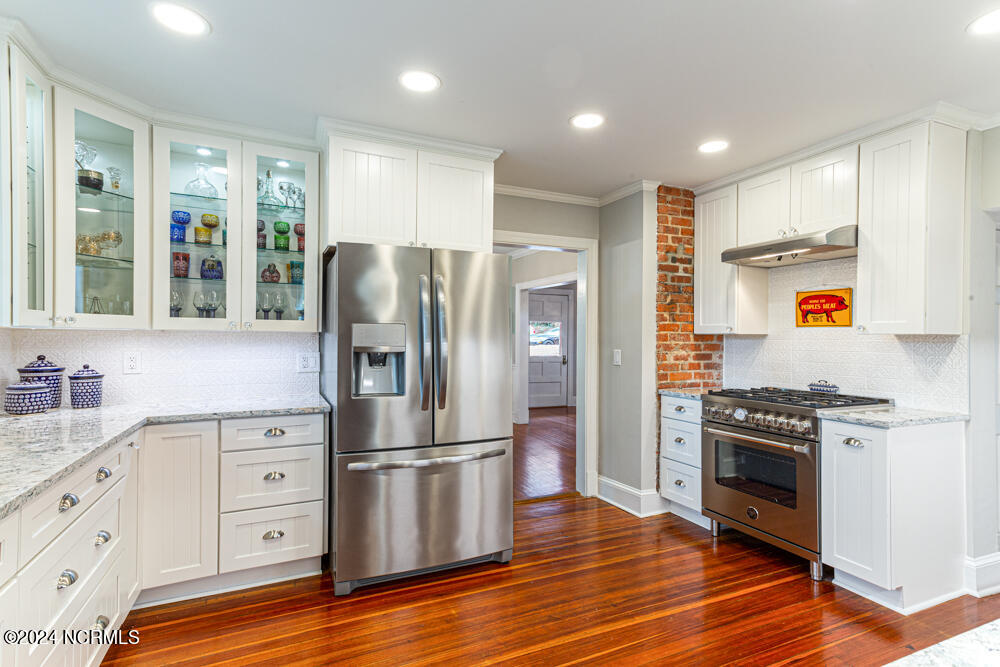 180 North Ridge Street Southern Pines, NC 28387 - Photo 33 of 72 Complete kitchen renovation with custom cabinetry with lighted glass upper cabinets, farm sink, Cambria quartz countertops, under cabinet lighting, and porcelain tile backsplash.