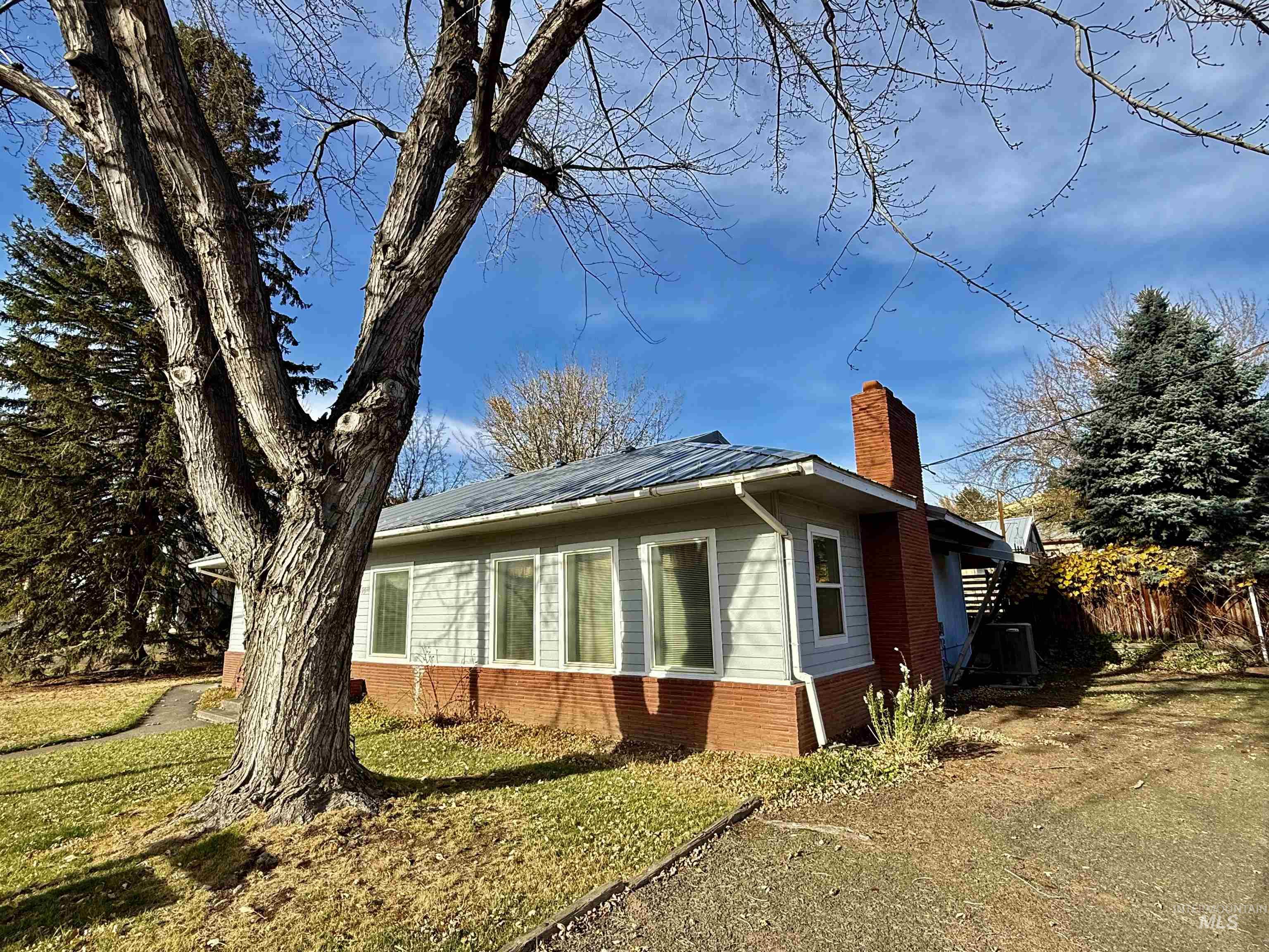 View of home's exterior featuring a metal roof, a chimney, brick siding, a standing seam roof, and a lawn