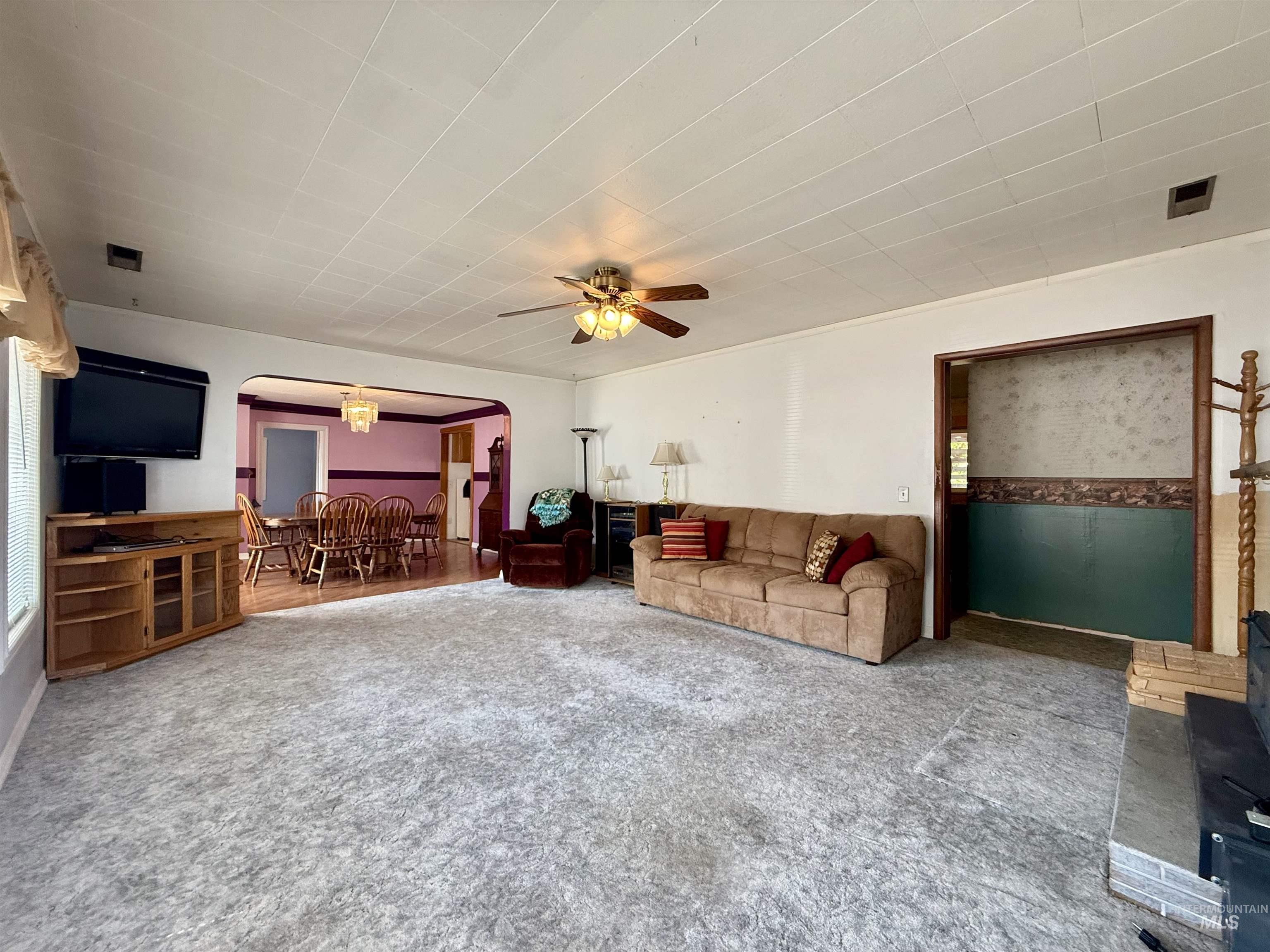 2395 Villard Street Pomeroy, WA 99347 - Photo 12 of 50 Living room with arched walkways, carpet flooring, ceiling fan, and a chandelier