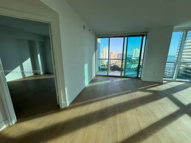 a view of an empty room with wooden floor and a window