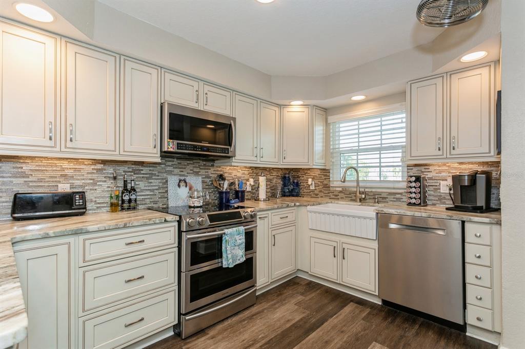 9166 Blind Pass Road St. Pete Beach, FL 33706 - Photo 10 of 37 a kitchen with white cabinets stainless steel appliances and sink
