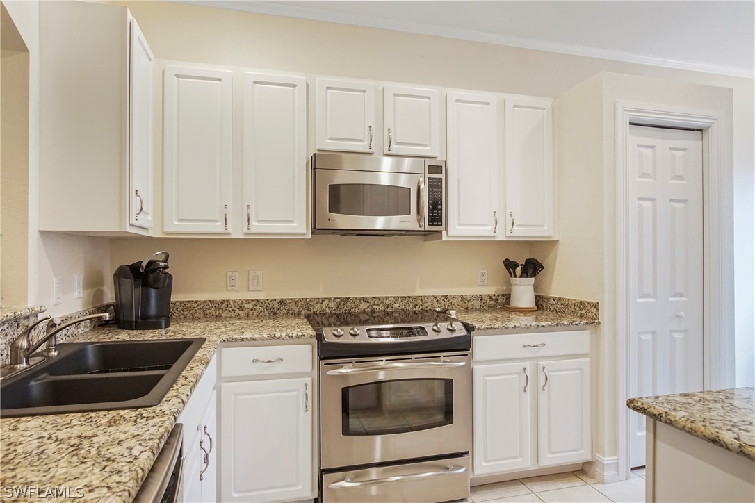 9070 Water Tupelo Road Fort Myers, FL 33912 - Photo 14 of 29 a kitchen with granite countertop white cabinets sink and stainless steel appliances