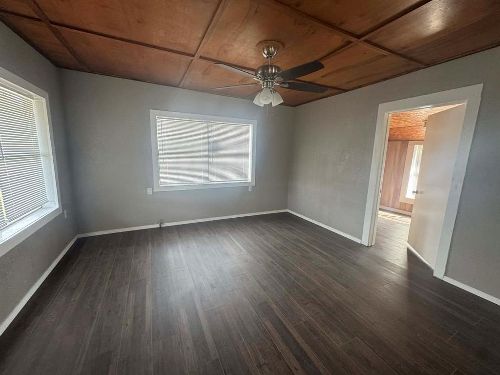 601 South Pine Street Comanche, TX 76442 - Photo 5 of 11 an empty room with wooden floor fan and windows