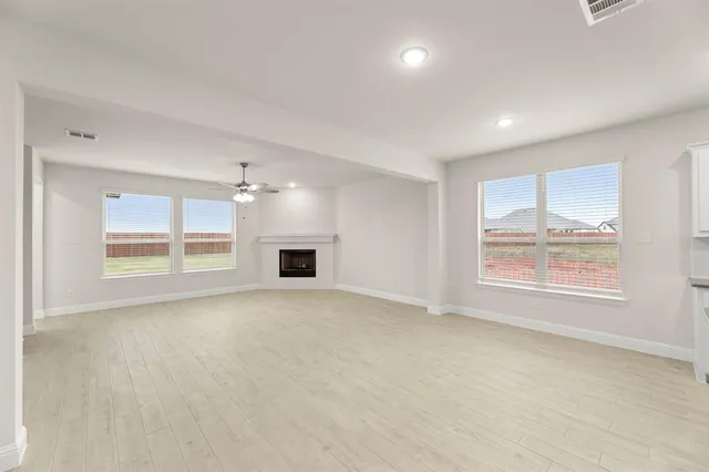 an empty room with windows and fireplace
