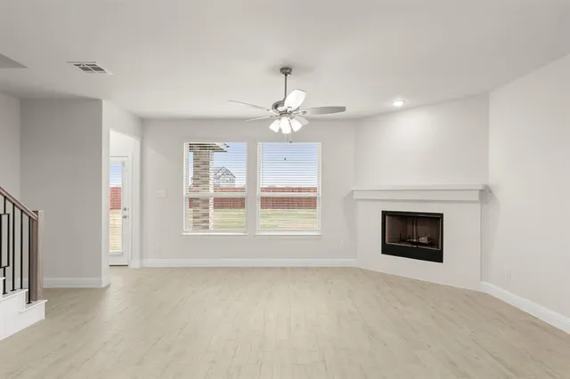 an empty room with chandelier fan and windows
