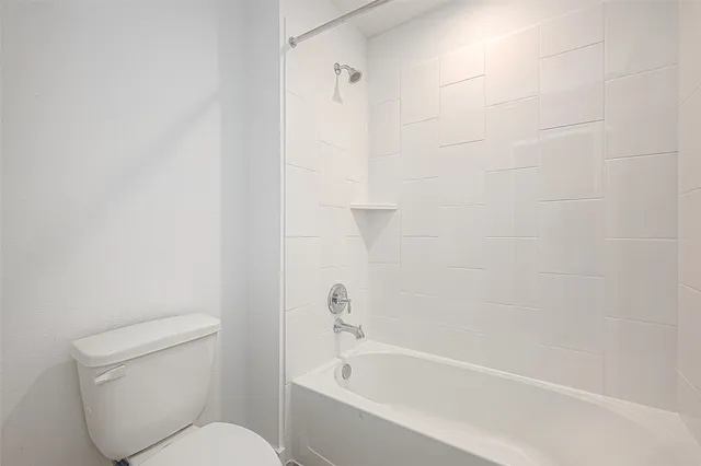 a white toilet sitting next to a bath tub