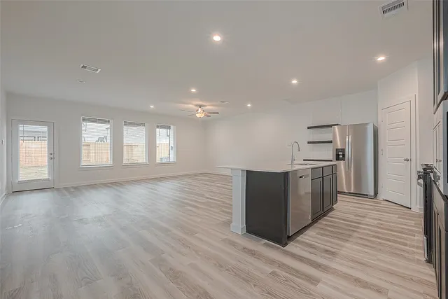 a kitchen with stainless steel appliances granite countertop a large counter top and wooden floors