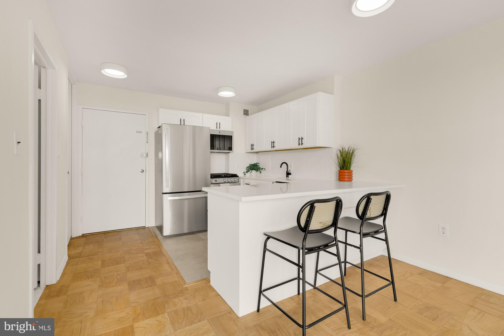 2800 Wisconsin Avenue Northwest, Unit 609 Washington, DC 20007 - Photo 11 of 20 a kitchen with stainless steel appliances a refrigerator a stove a sink and white cabinets with wooden floor