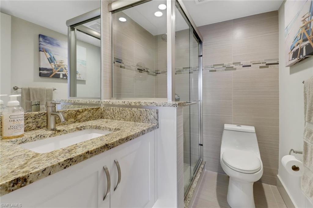 3055 Riviera Drive, Unit 201 Naples, FL 34103 - Photo 10 of 18 Ensuite bath featuring tile walls, vanity, a stall shower, light tile patterned floors, and recessed lighting