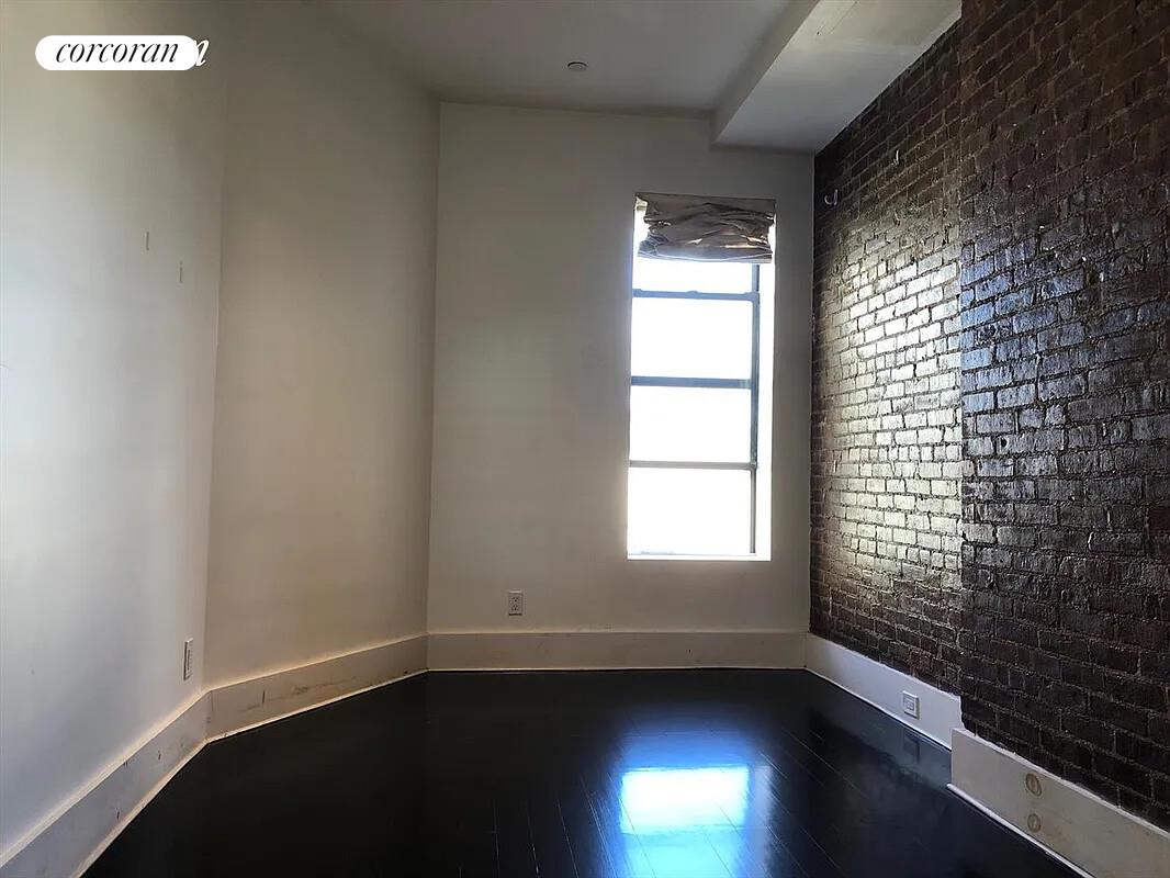 764 St Nicholas Avenue, Unit PH Manhattan, NY 10031 - Photo 12 of 14 a view of an empty room with wooden floor and a window