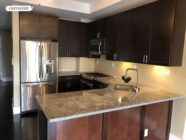 a kitchen with granite countertop a sink a stove and refrigerator